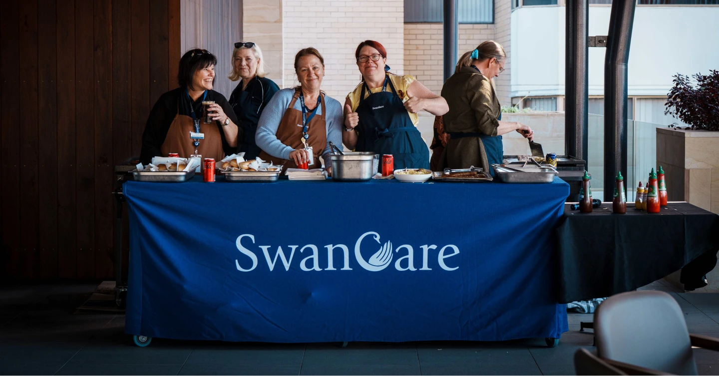 SwanCare team members serving food together at a community barbecue